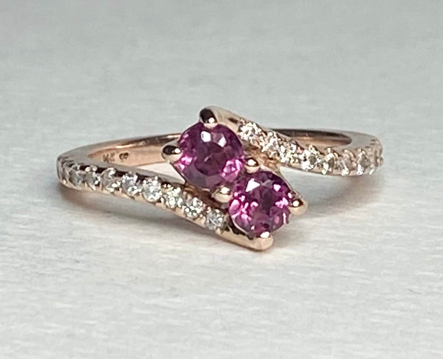 14k rose gold ring with two pink rhodolite garnets and diamonds.