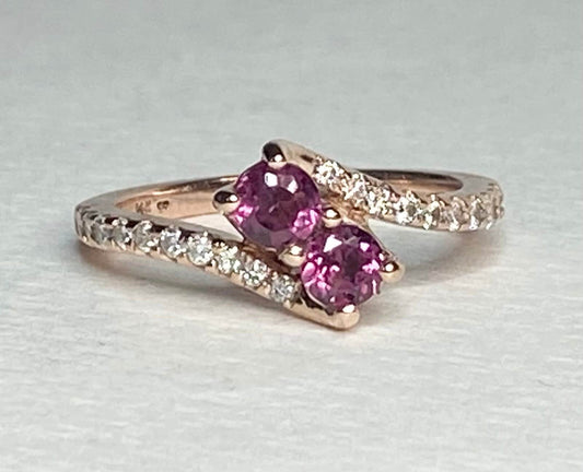 14k rose gold ring with two pink rhodolite garnets and diamonds.