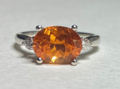 Sterling silver ring with a large orange spessartite garnet and two lab-grown diamonds.