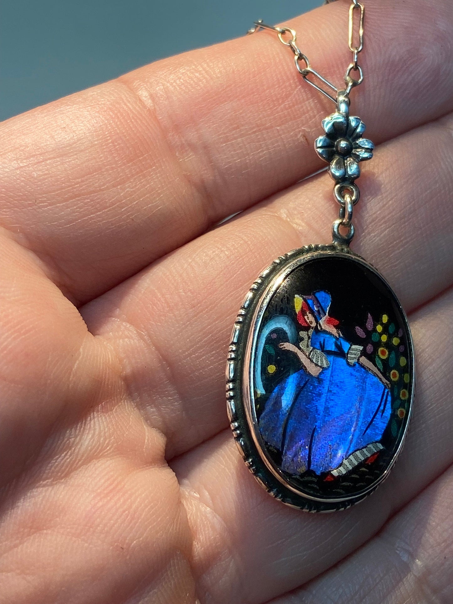 Reverse painted Morpho butterfly pendant necklace with a lady in a garden.