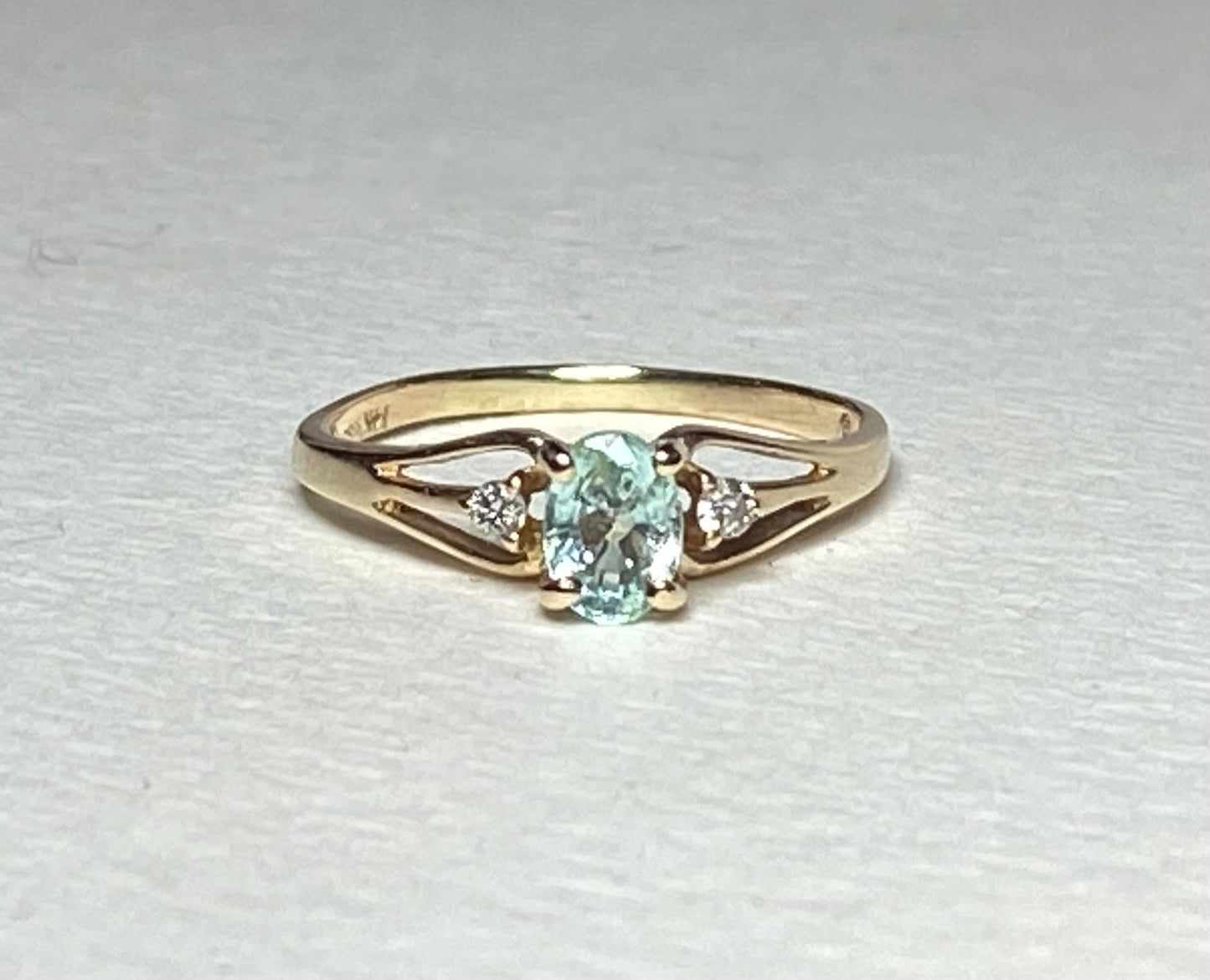 14k gold ring with oval paraiba colored tourmaline and two diamonds.