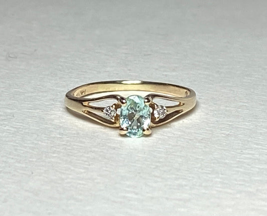 14k gold ring with oval paraiba colored tourmaline and two diamonds.