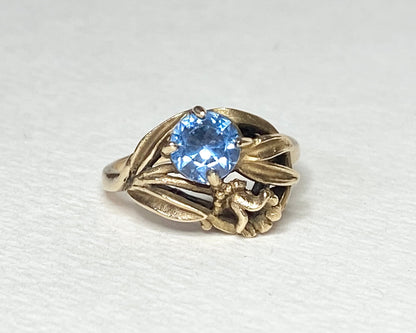 Art Nouveau style 10k yellow gold ring with a blue spinel and floral motif.