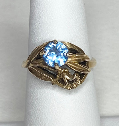 Art Nouveau style 10k yellow gold ring with a blue synthetic spinel and floral design.
