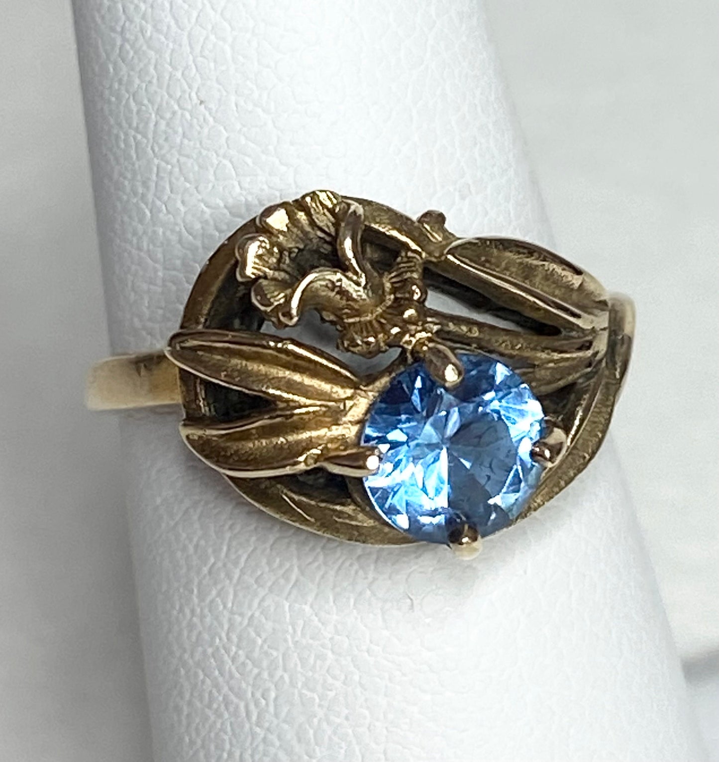 Art Nouveau style 10k yellow gold ring with a blue synthetic spinel and floral motif.