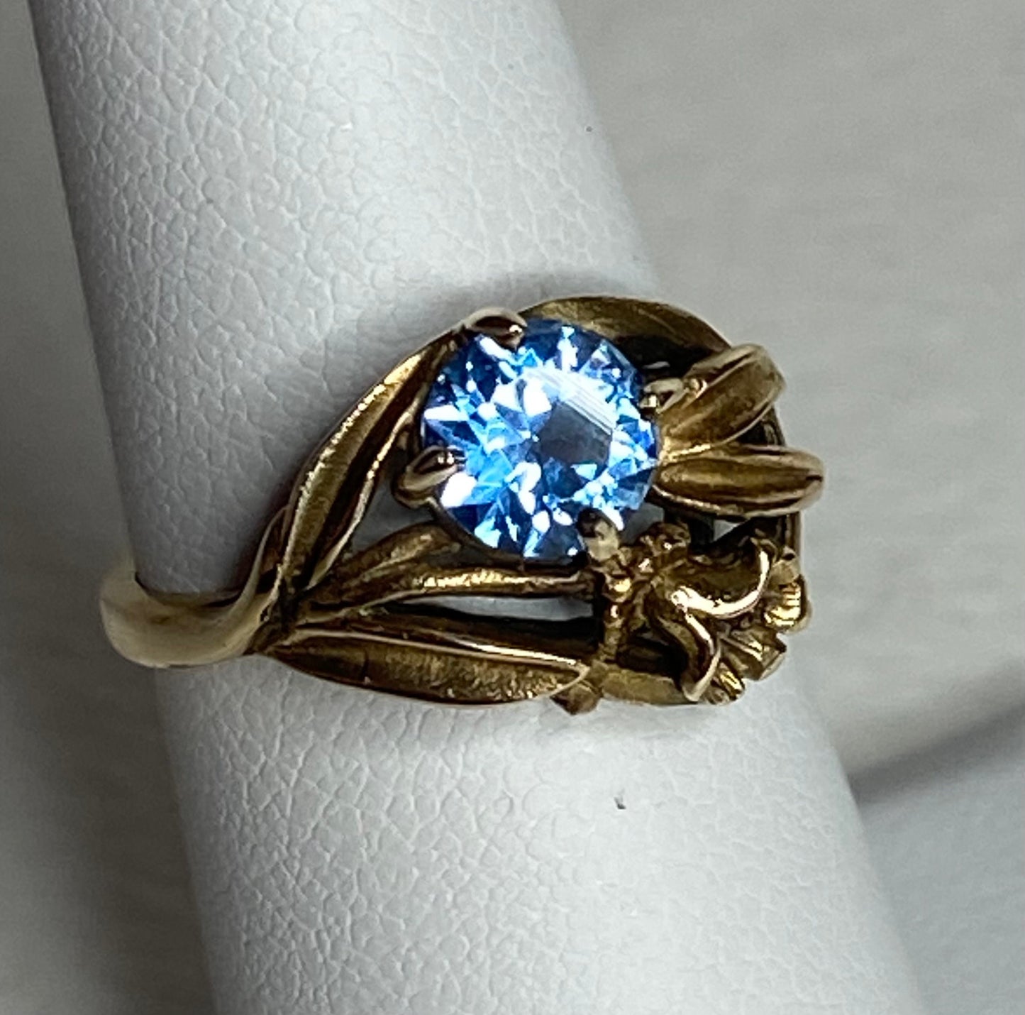 Art Nouveau style 10k yellow gold ring with a blue synthetic spinel and floral design.