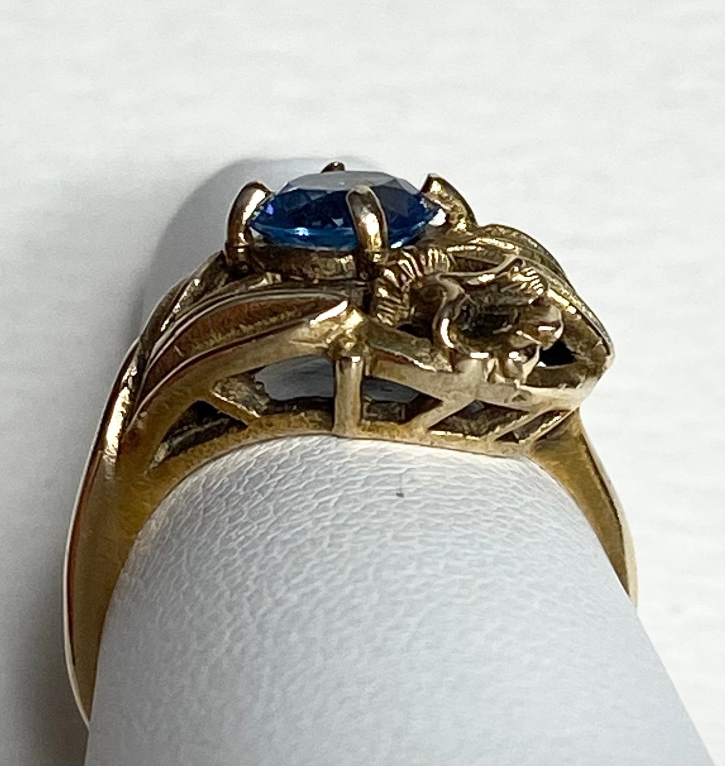 Art Nouveau style 10k yellow gold ring with a blue synthetic spinel and floral accents.