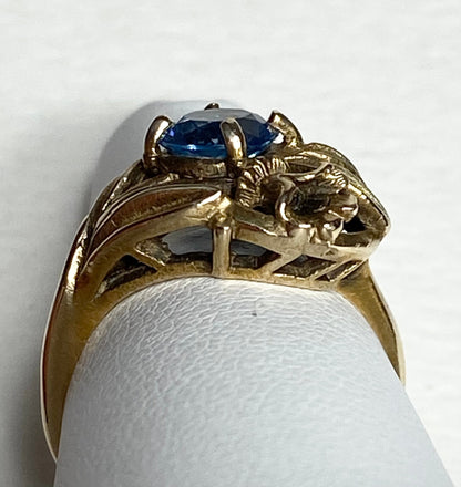 Art Nouveau style 10k yellow gold ring with a blue synthetic spinel and floral accents.