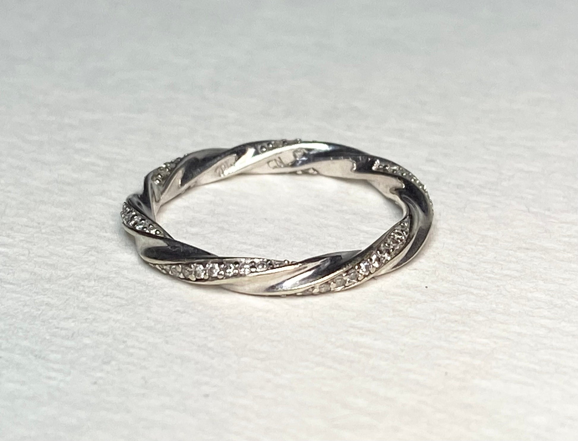 A twisted 10k white gold eternity band ring with 72 small diamonds.