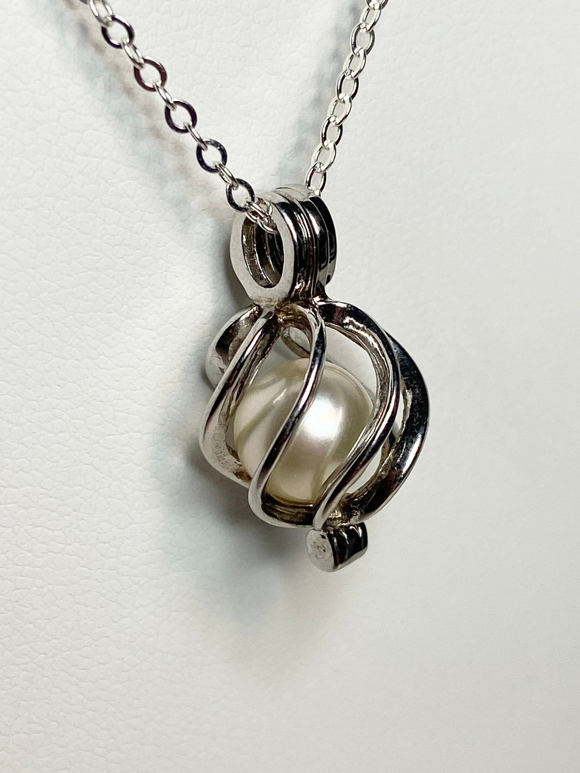 Sterling silver cage pendant with a soft cream Akoya pearl on a cable chain.