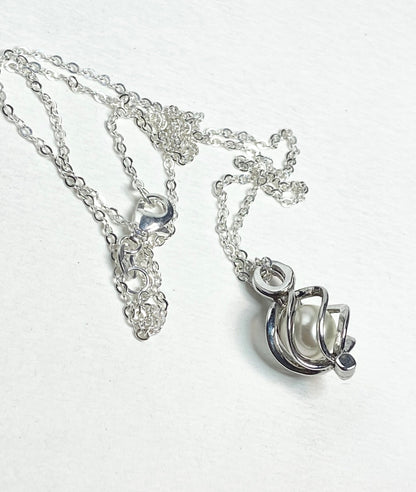 Sterling silver necklace with a pearl pendant in a cage.