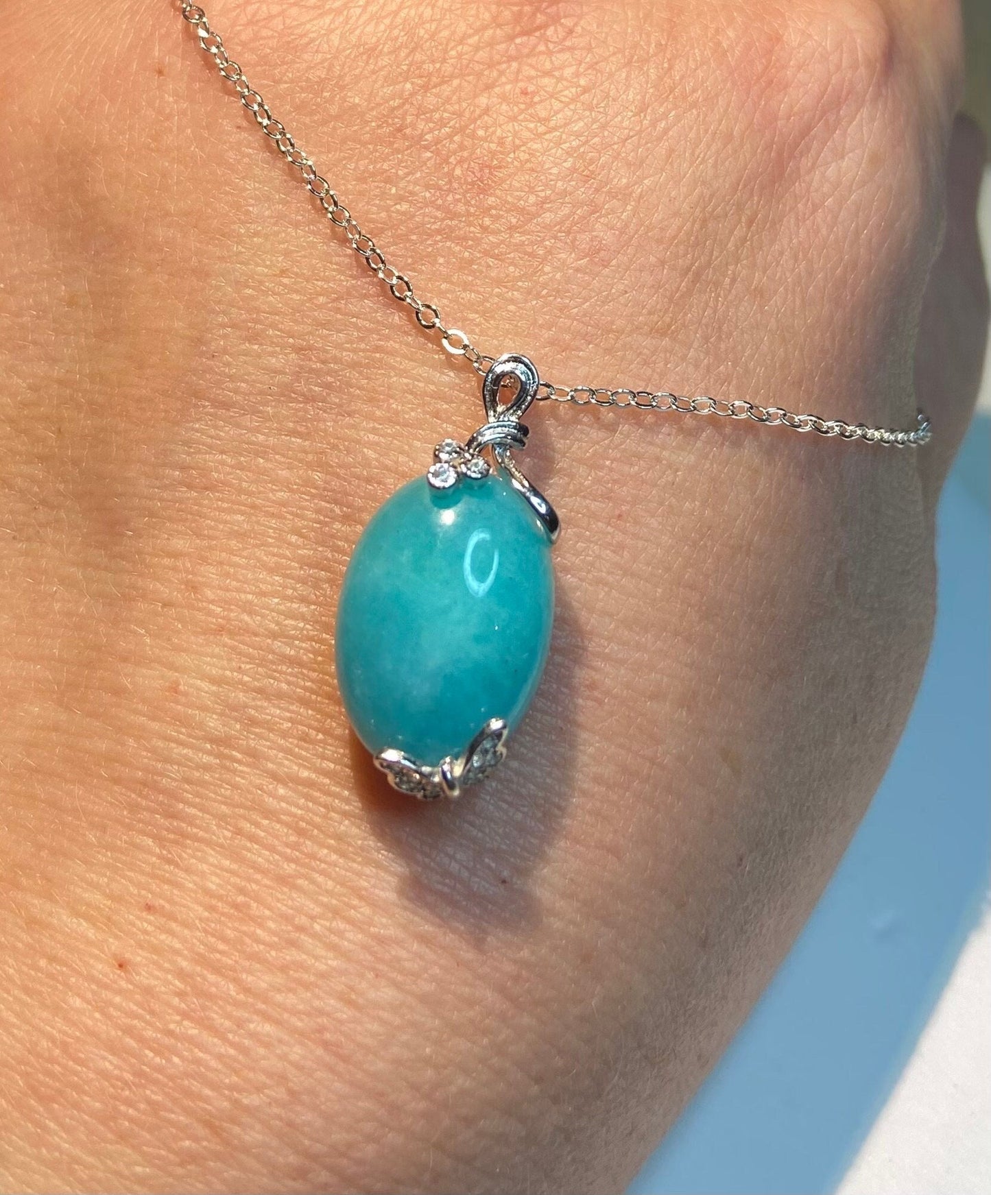 Sterling silver necklace with oval Peruvian amazonite pendant and butterfly floral motif.