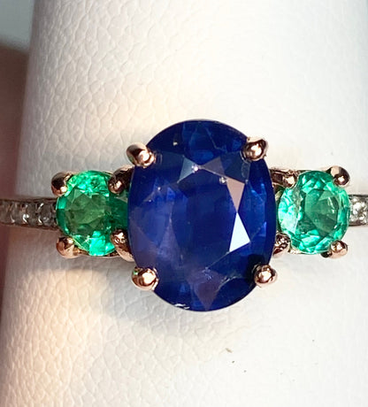 Oval blue sapphire ring with emeralds and diamonds in rose gold.