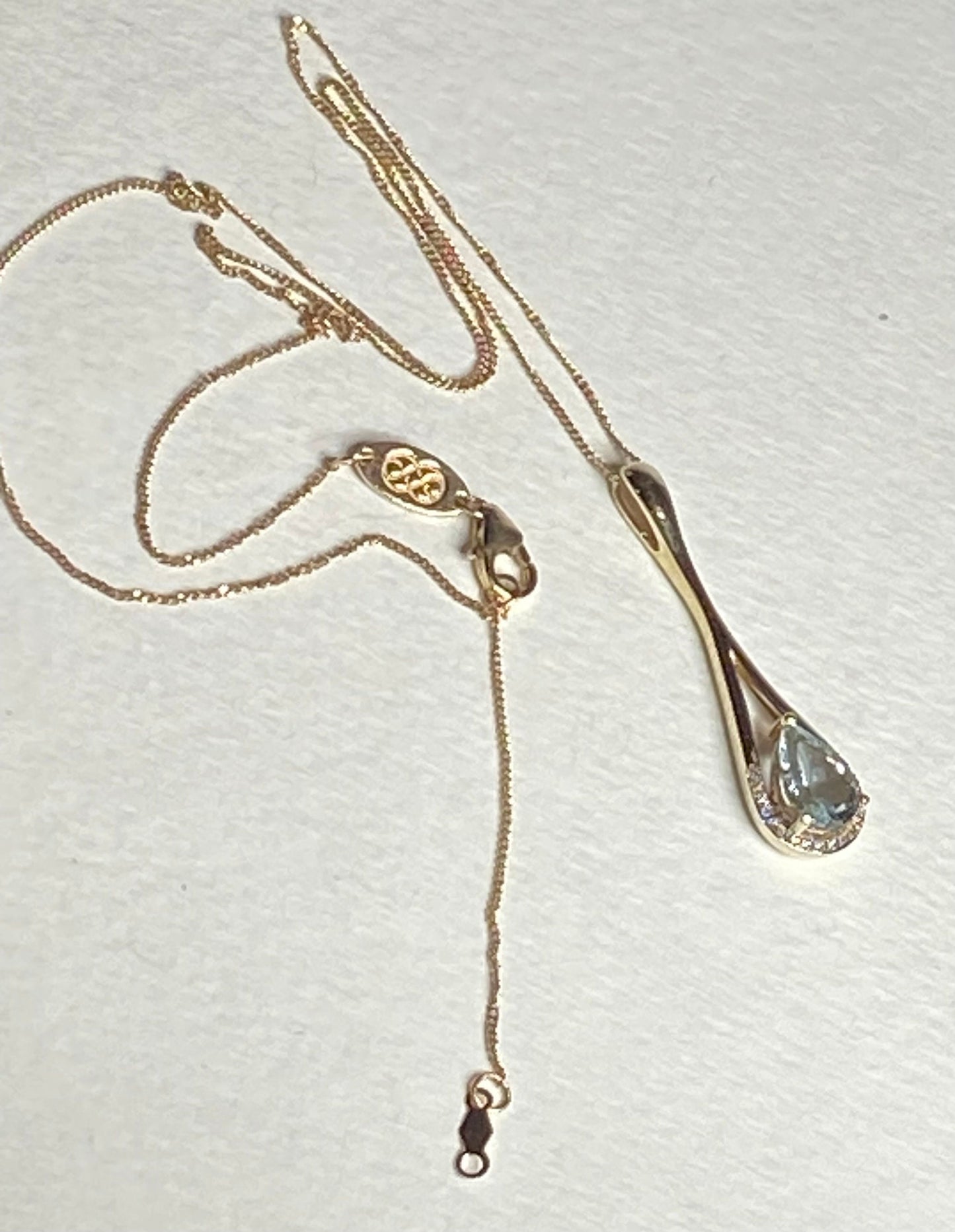 Gold necklace with a pear-shaped aquamarine and diamond pendant.