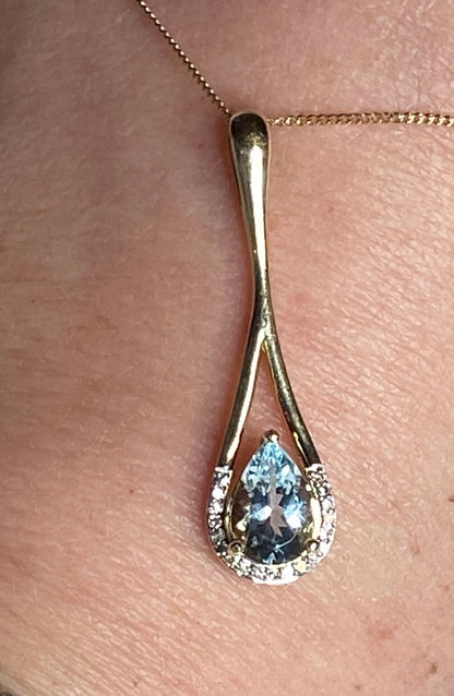 A pear-shaped aquamarine pendant with diamonds on a gold chain.