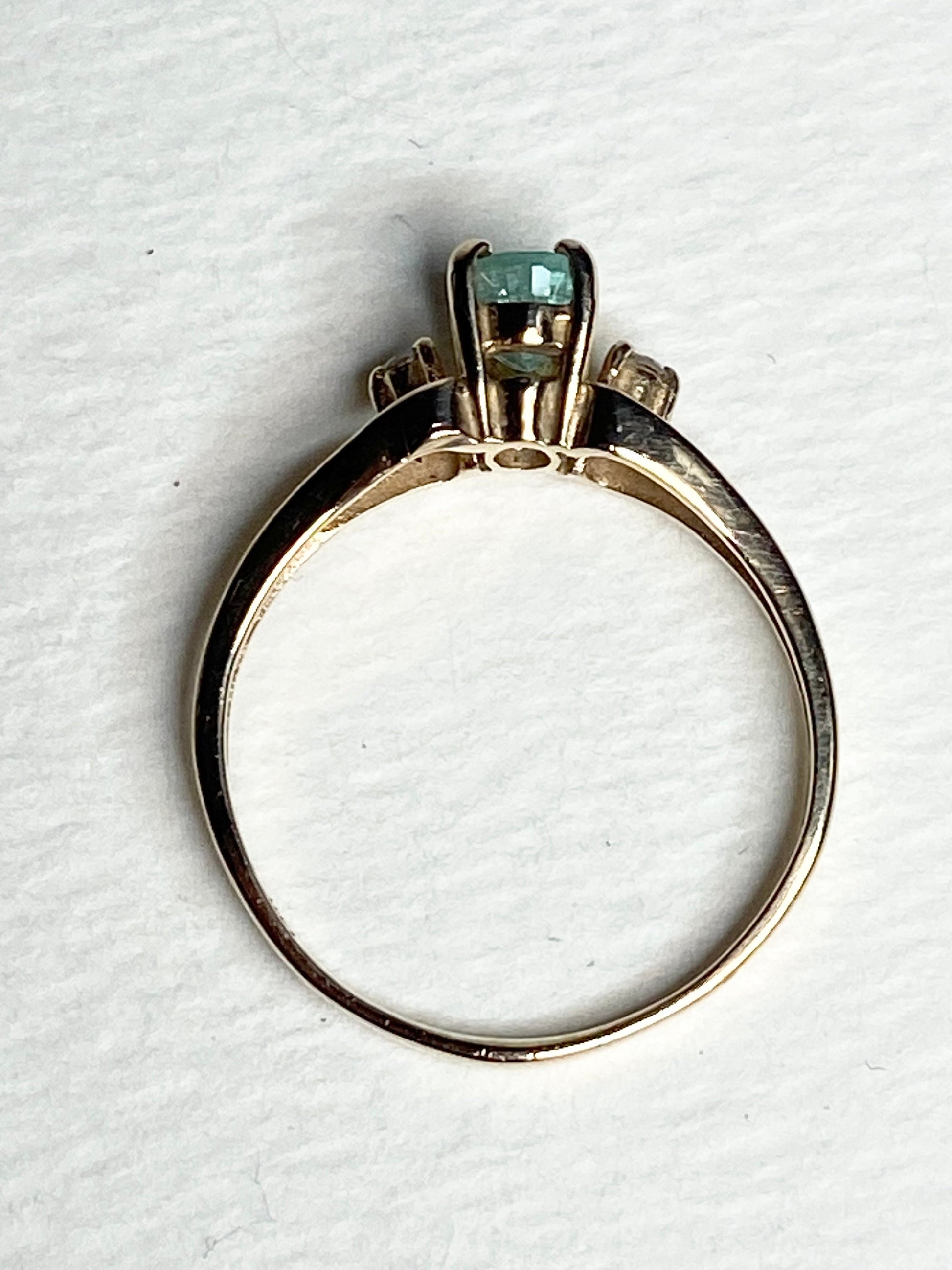 A 14k gold ring with a green tourmaline and two diamonds.