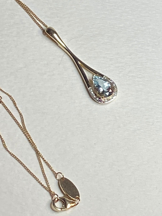 A long teardrop pendant with aquamarine and diamonds on a gold chain.