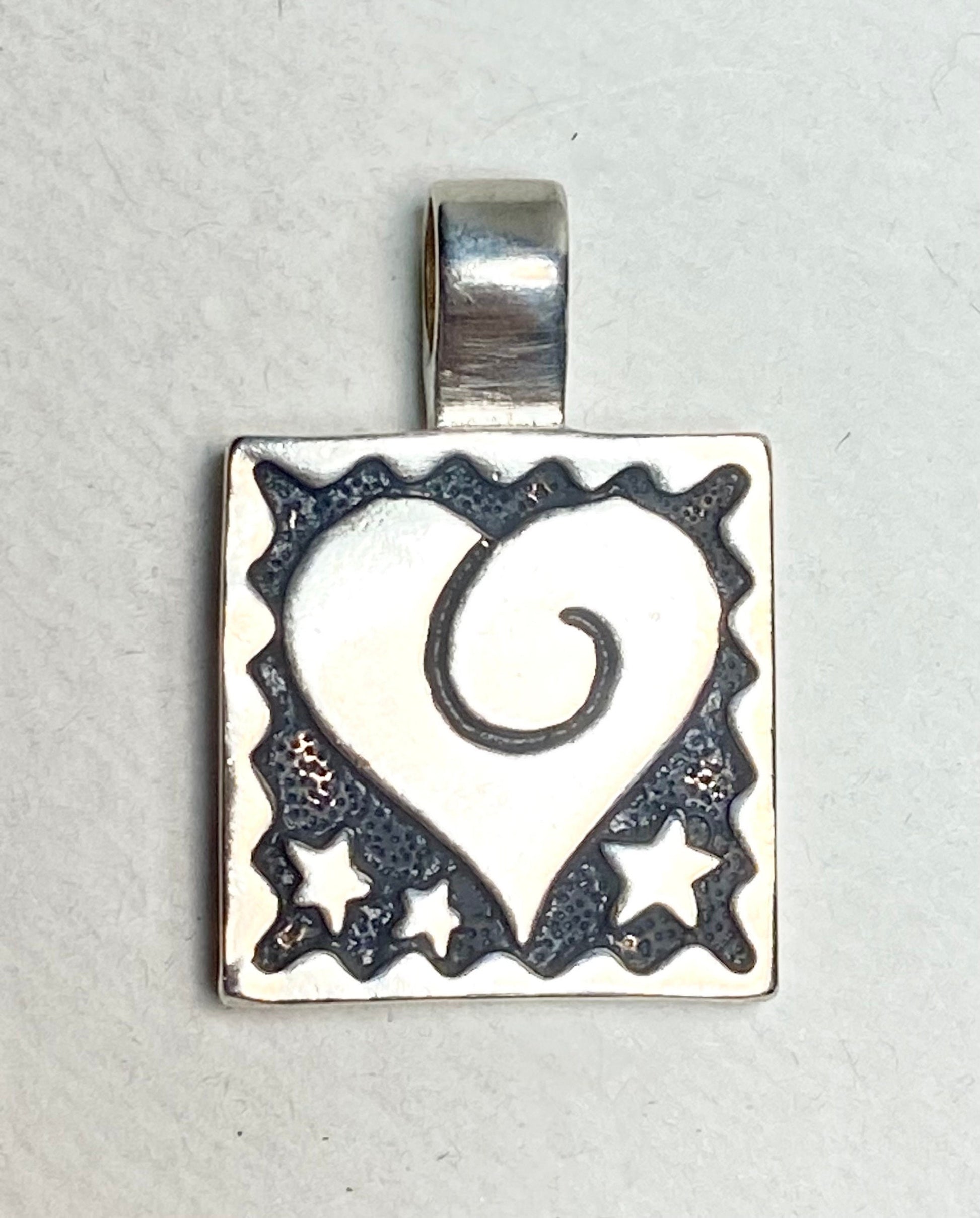 Sterling silver square pendant with a heart and stars design.