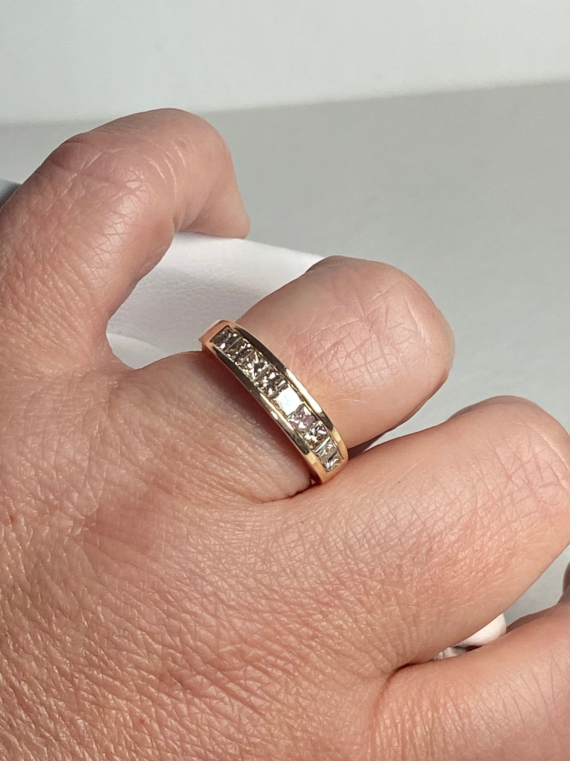 A 14k yellow gold band ring with channel-set princess-cut diamonds.