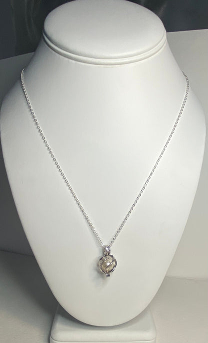 Soft cream Akoya pearl in a sterling silver cage pendant on a sterling silver necklace.