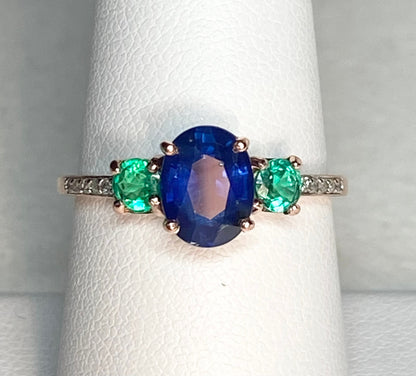 Oval blue sapphire ring with emeralds and diamonds in rose gold.