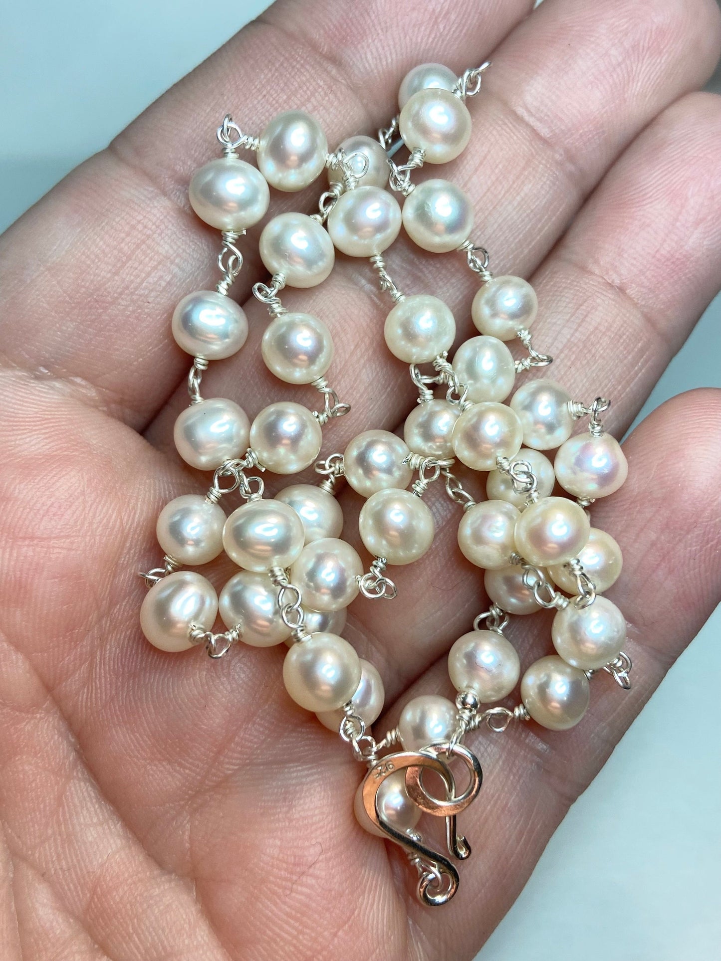 A sterling silver necklace with lustrous freshwater pearls and a hook clasp.