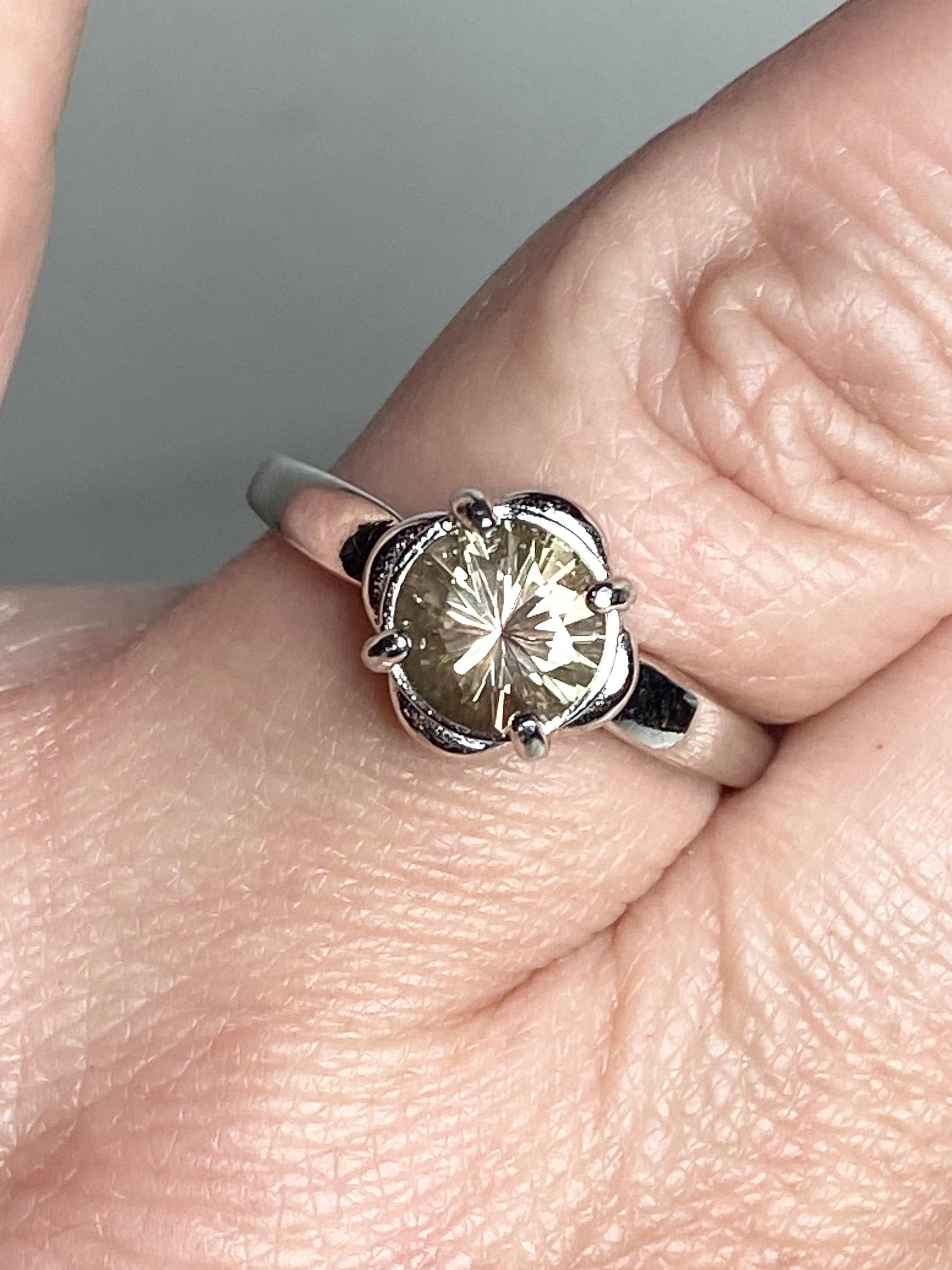 Sterling silver ring with a round, color-shifting Oregon Sunstone in a floral setting.