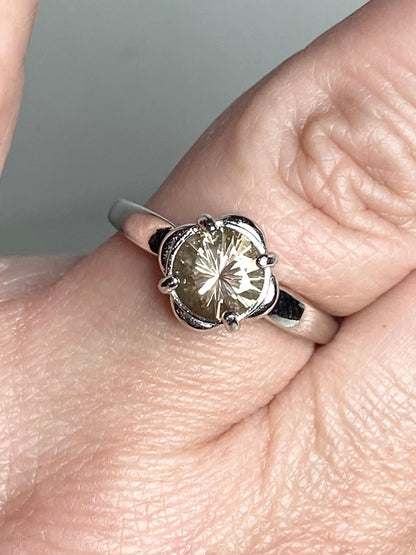Sterling silver ring with a round, color-shifting Oregon Sunstone in a floral setting.