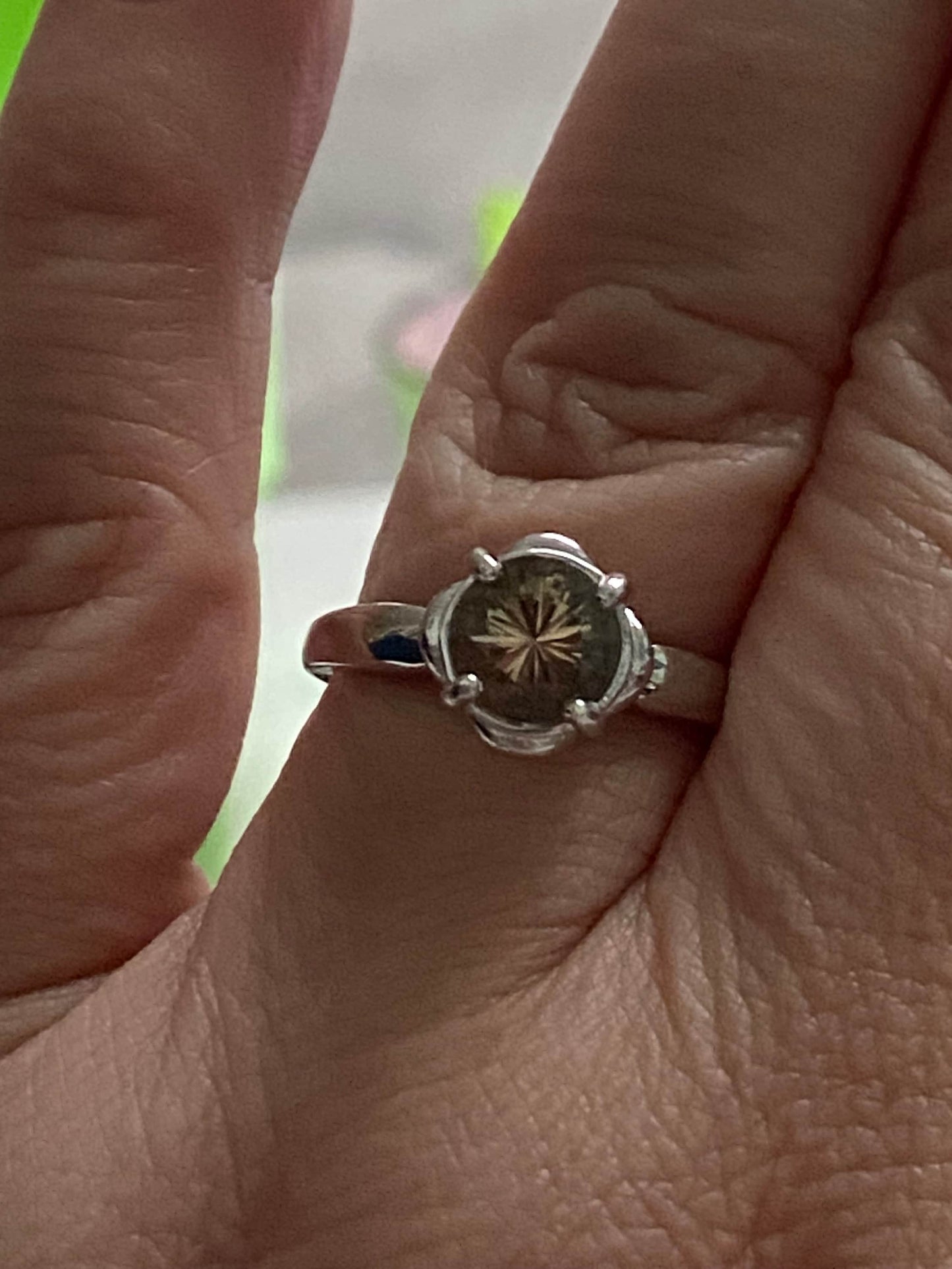 Sterling silver ring with a round, 1.18ct Oregon Sunstone in a floral setting.