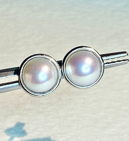 Two cultured pearl halves set in sterling silver bezels.