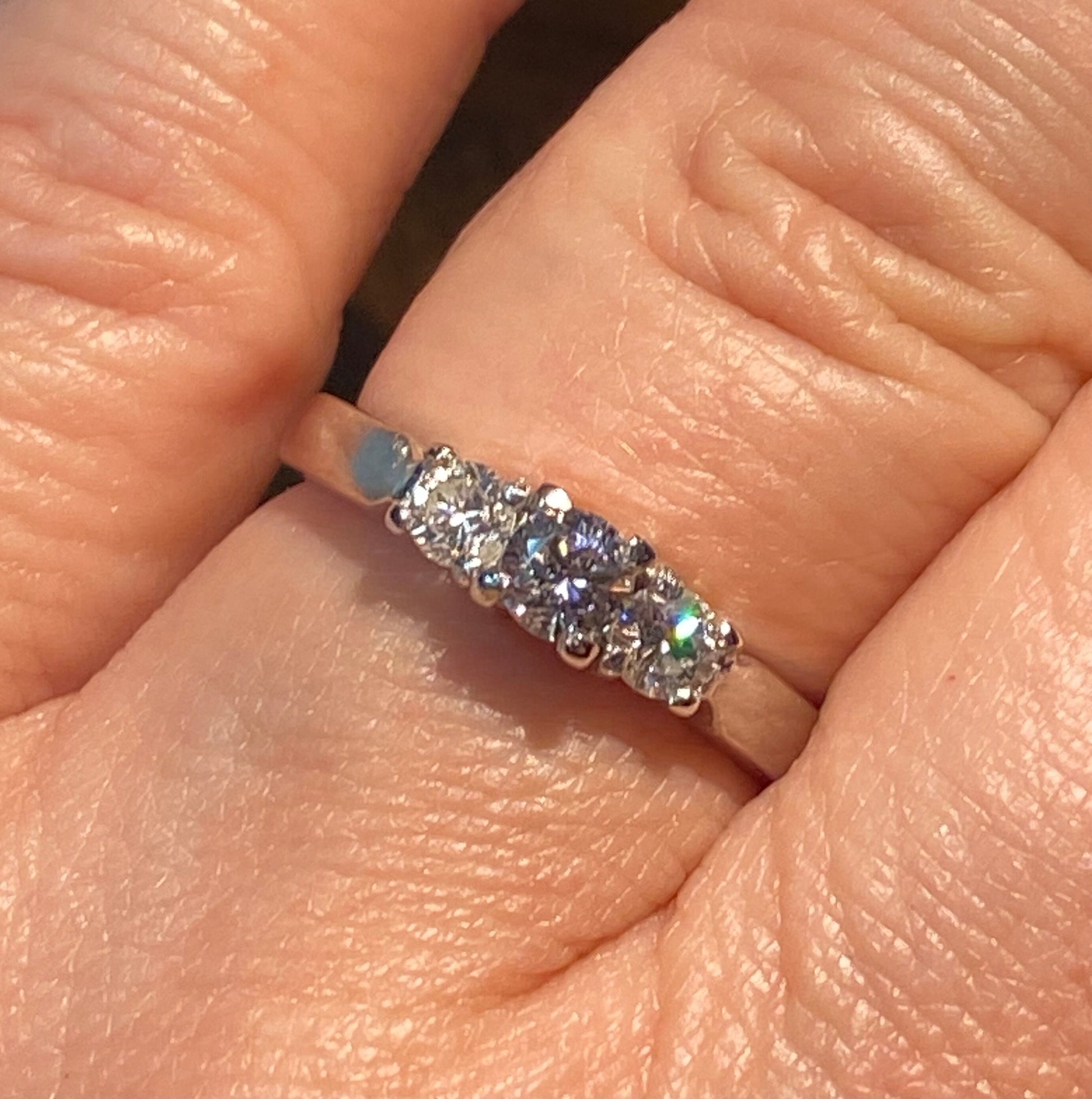 Platinum ring with three diamonds, including a very light pink center stone.