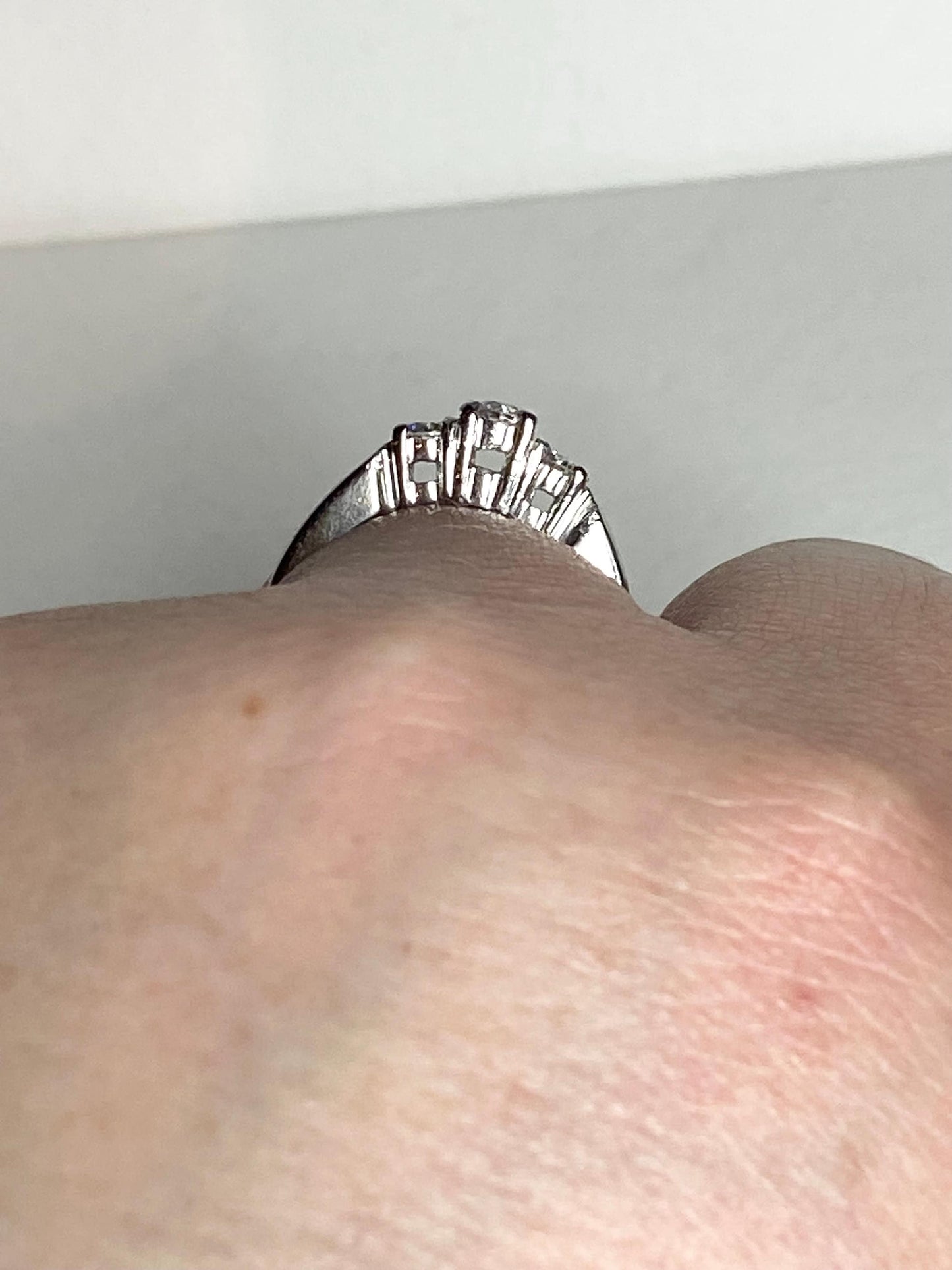 Platinum ring with three diamonds, including a very light pink center stone.
