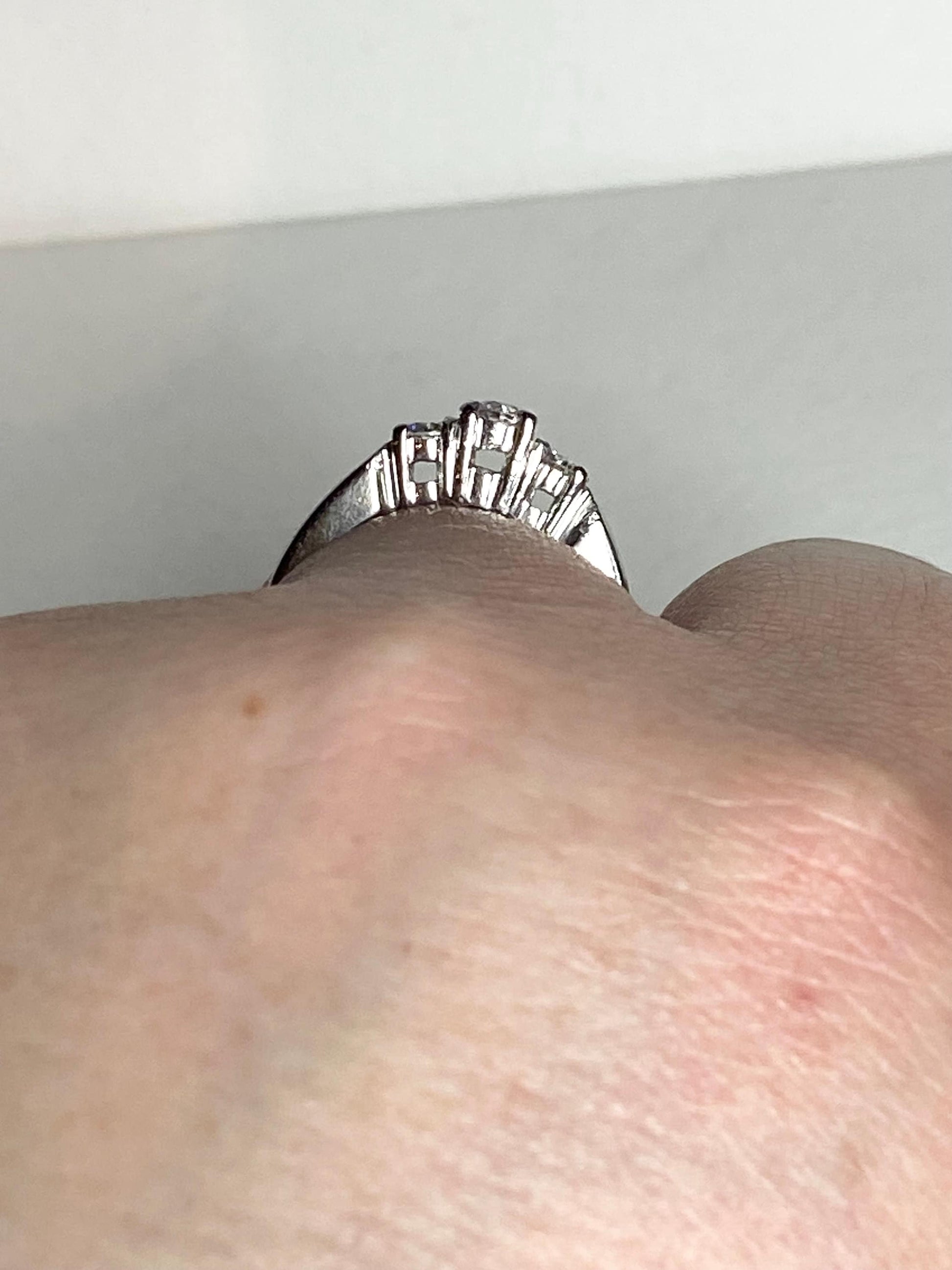 Platinum ring with three diamonds, including a very light pink center stone.