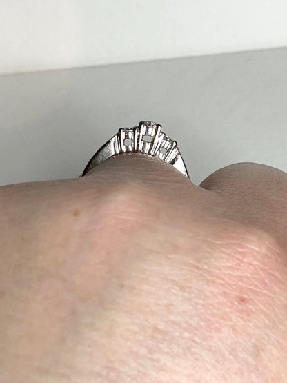 Platinum ring with three diamonds, including a very light pink center stone.