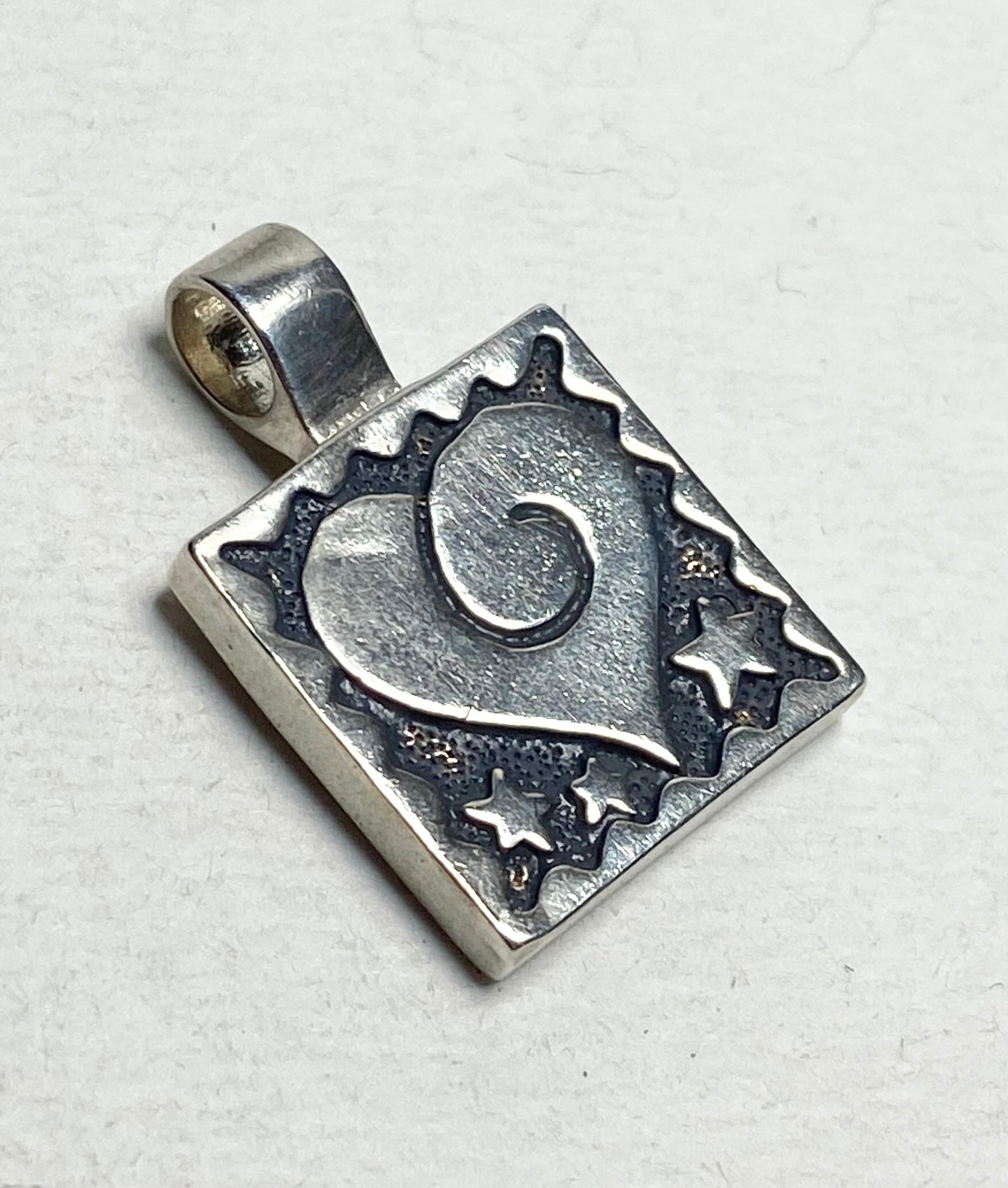 Sterling silver square pendant with a heart and stars design.