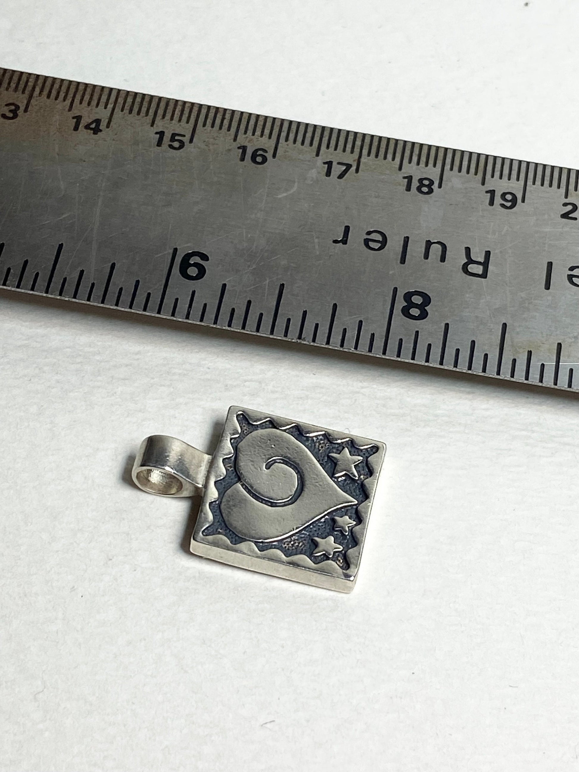 Sterling silver square pendant with a heart and stars design.