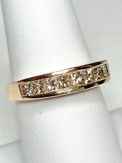 A 14k yellow gold band ring with channel-set princess-cut diamonds.