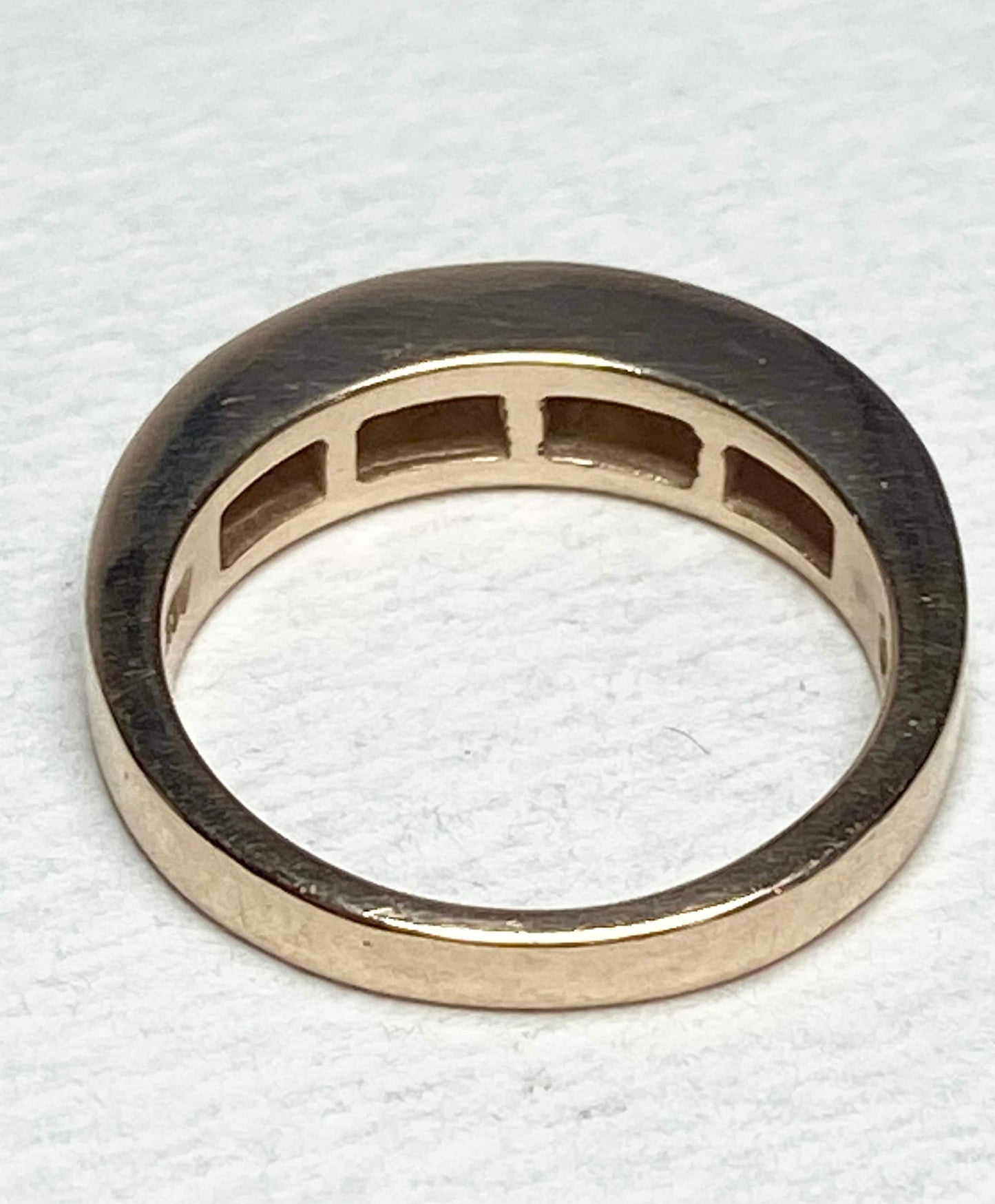 A 14k yellow gold band ring with channel-set princess-cut diamonds.