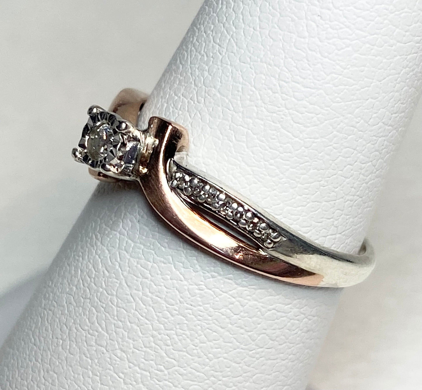 A bypass ring with a diamond solitaire and accent diamonds in rose gold and sterling silver.