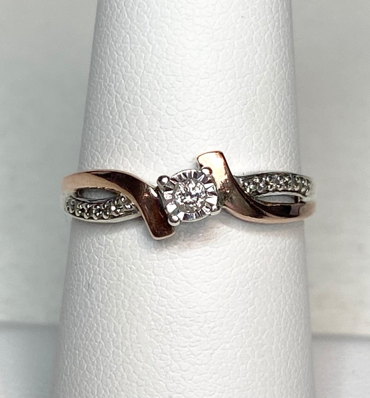 Bypass ring with rose gold, sterling silver, and a central diamond.