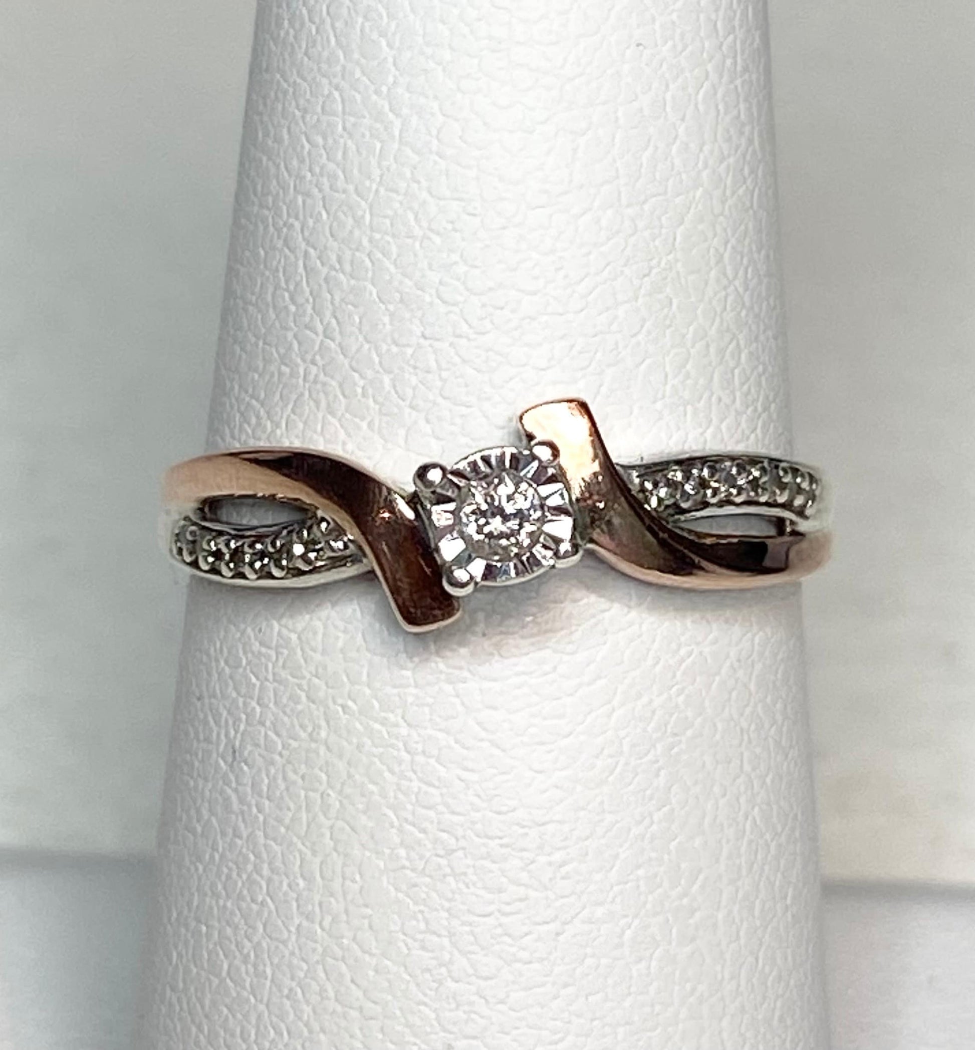 Bypass ring with rose gold, sterling silver, and a central diamond.