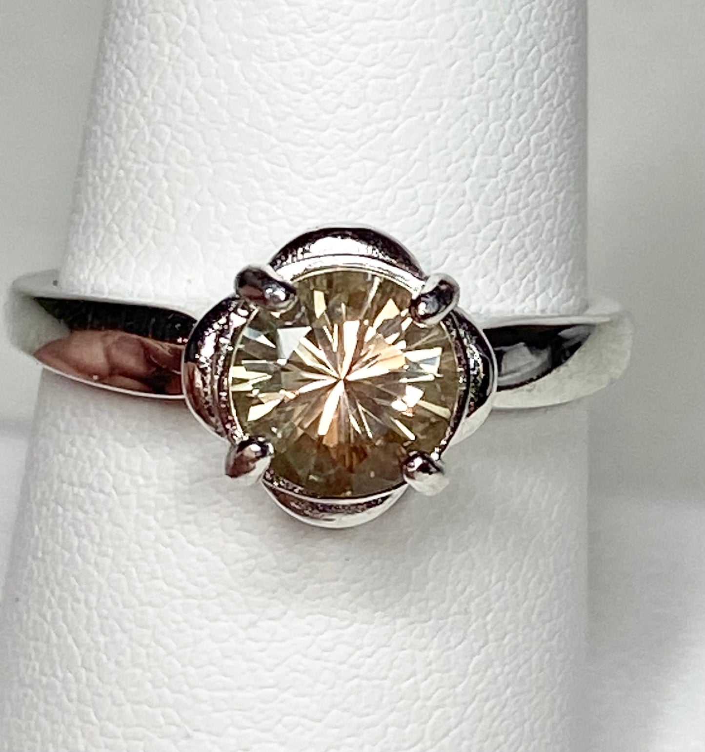 Sterling silver ring with a round, color-shifting Oregon Sunstone in a floral setting.