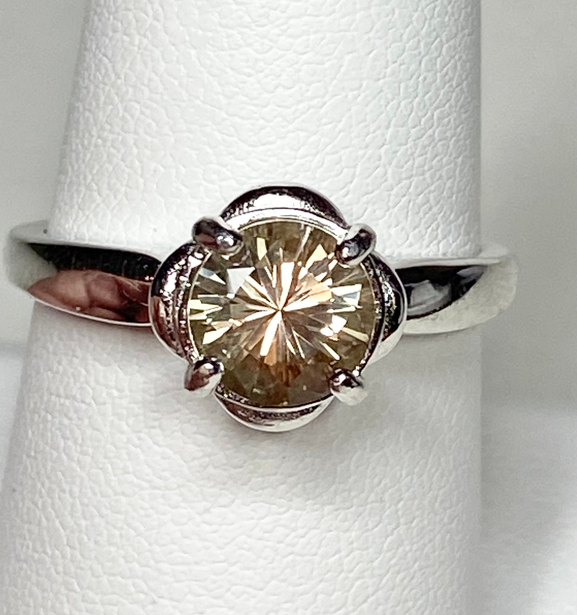 Sterling silver ring with a round, color-shifting Oregon Sunstone in a floral setting.