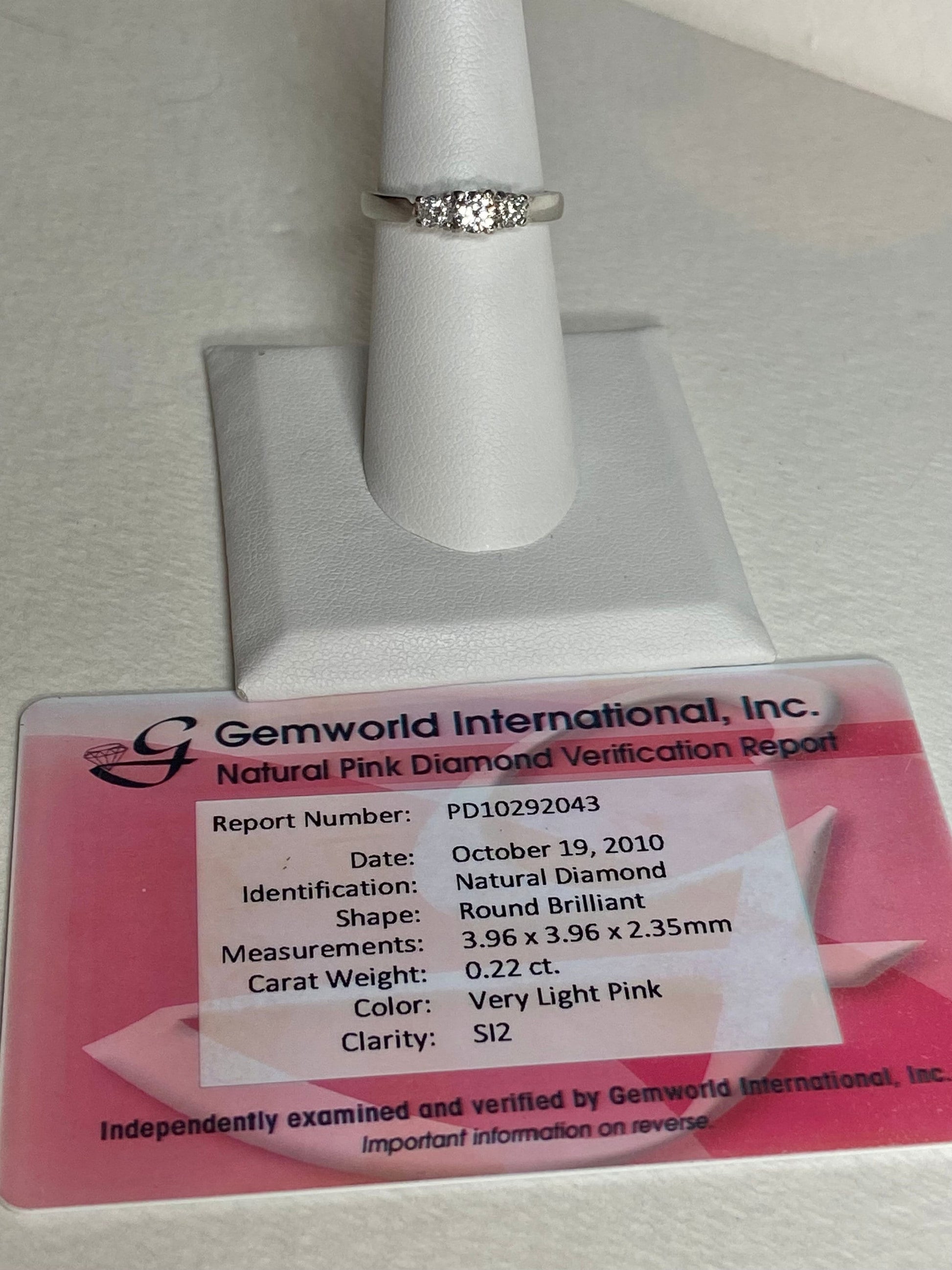 Platinum 3-stone ring with a .22ct very light pink diamond and two white diamonds.