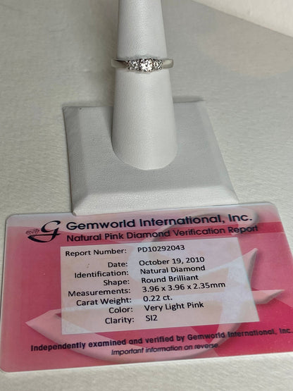 Platinum 3-stone ring with a .22ct very light pink diamond and two white diamonds.