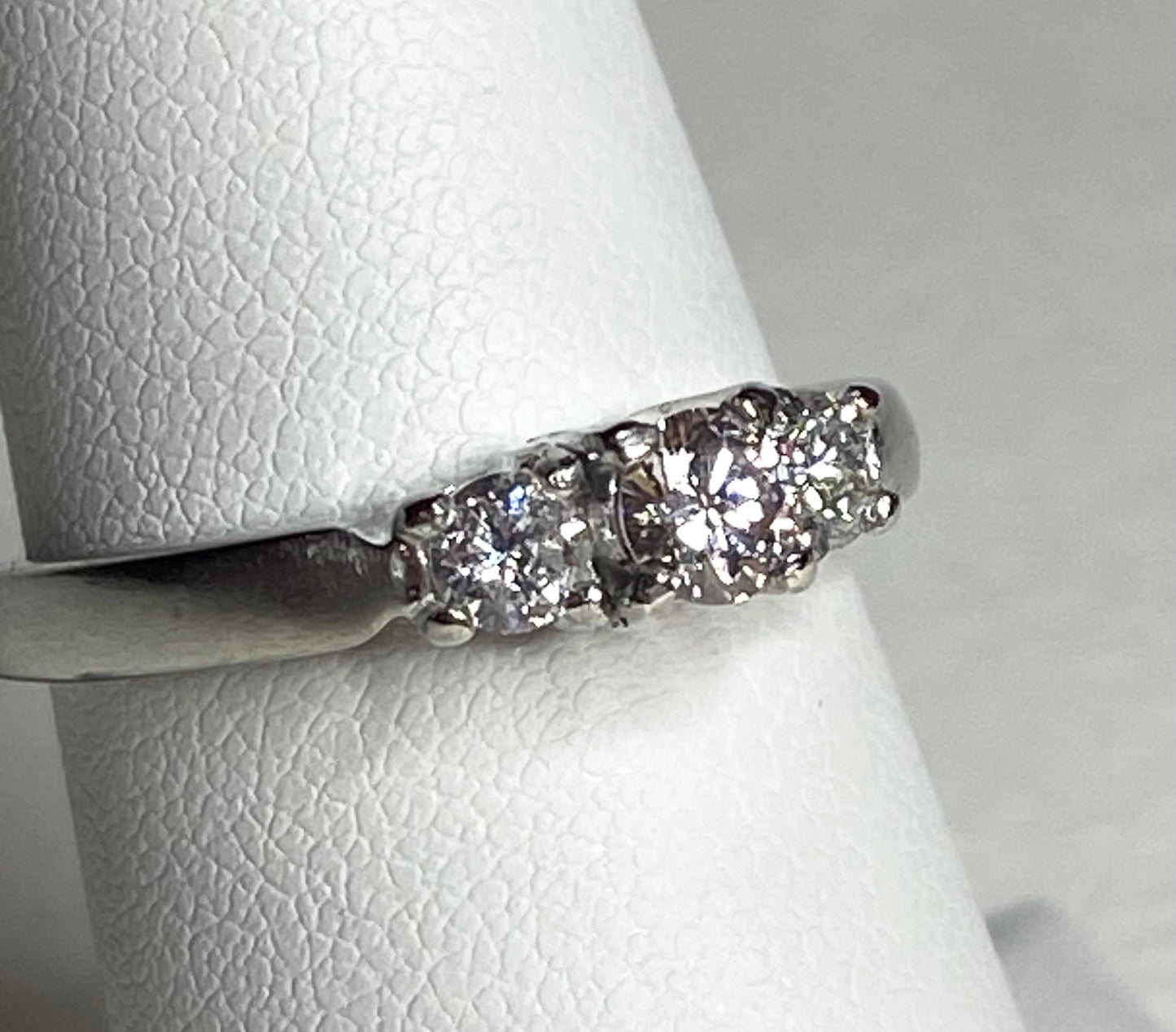Platinum three-stone ring with a light pink diamond and two white diamonds.
