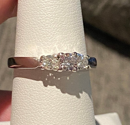 Platinum ring with a very light pink diamond and two white diamonds.