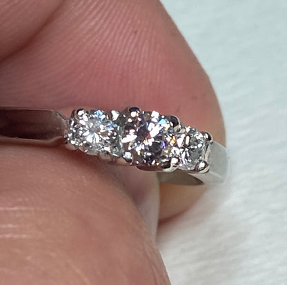 Platinum ring with three diamonds, including a very light pink center diamond.