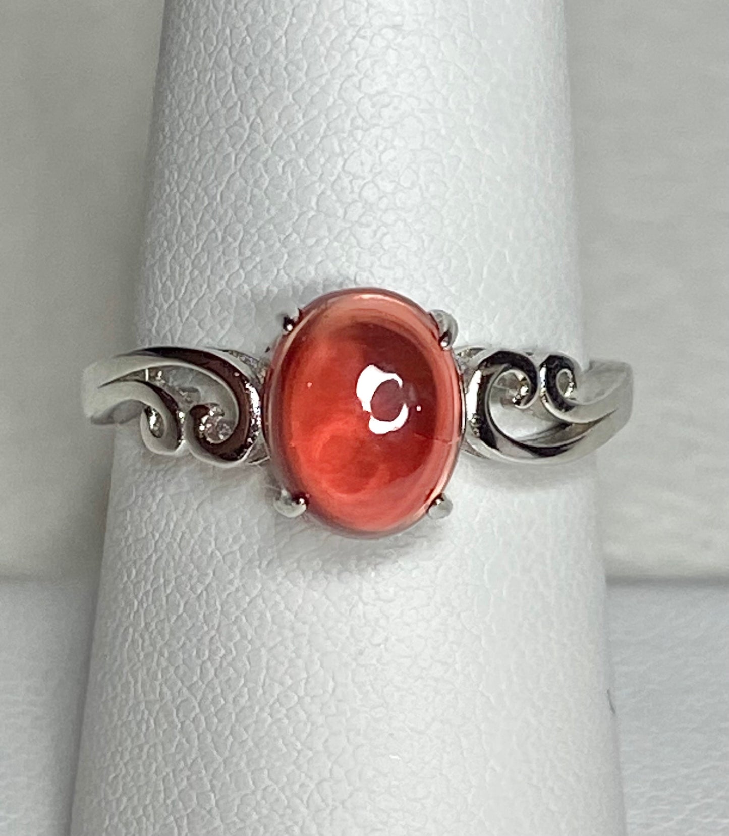 Sterling silver ring with a red Oregon sunstone cabochon and swirl details.