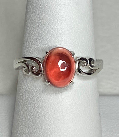 Sterling silver ring with a red Oregon sunstone cabochon and swirl details.